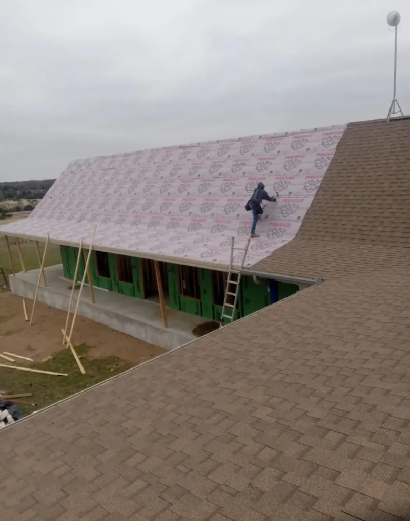 Worker preparing underlayment for a metal roof installation in Spanish Lake